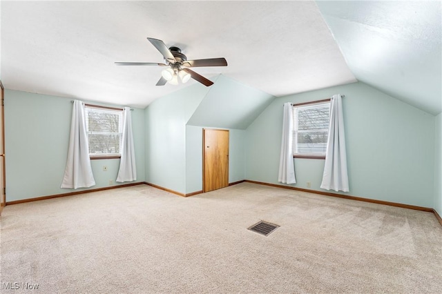 additional living space with ceiling fan, carpet floors, a healthy amount of sunlight, and lofted ceiling