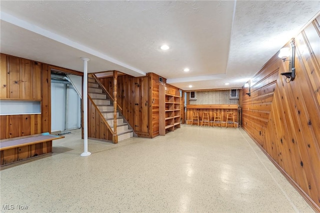 basement with a textured ceiling and wood walls