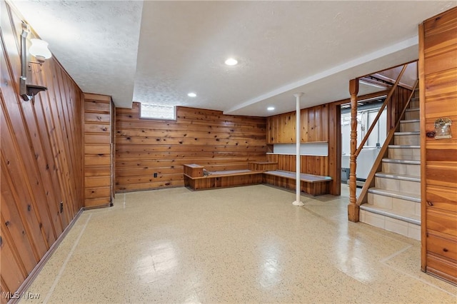 basement featuring a textured ceiling and wooden walls