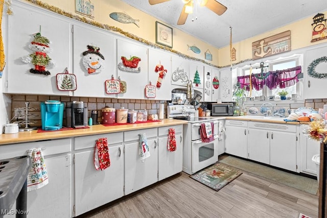 kitchen featuring ceiling fan, light hardwood / wood-style floors, electric stove, decorative backsplash, and white cabinets