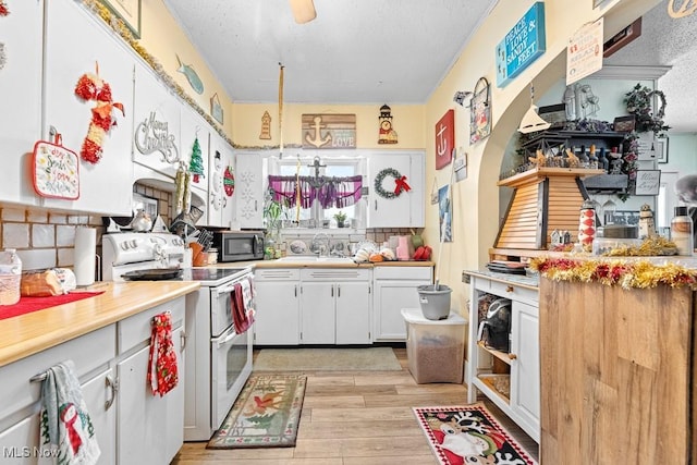 kitchen with white range with electric cooktop, sink, white cabinets, and a textured ceiling