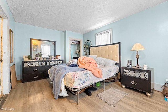 bedroom featuring a textured ceiling, light hardwood / wood-style flooring, and a closet