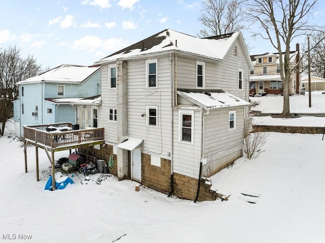 snow covered house featuring a wooden deck