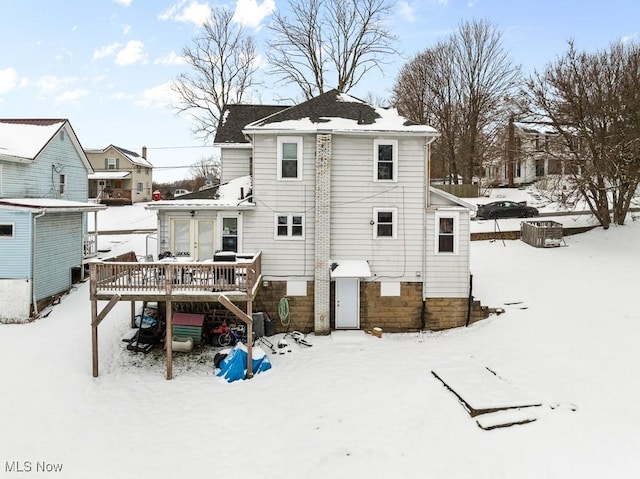 snow covered rear of property with a deck