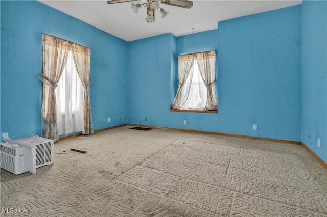 carpeted spare room featuring ceiling fan, plenty of natural light, and an AC wall unit