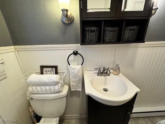 bathroom with vanity, toilet, and a baseboard heating unit