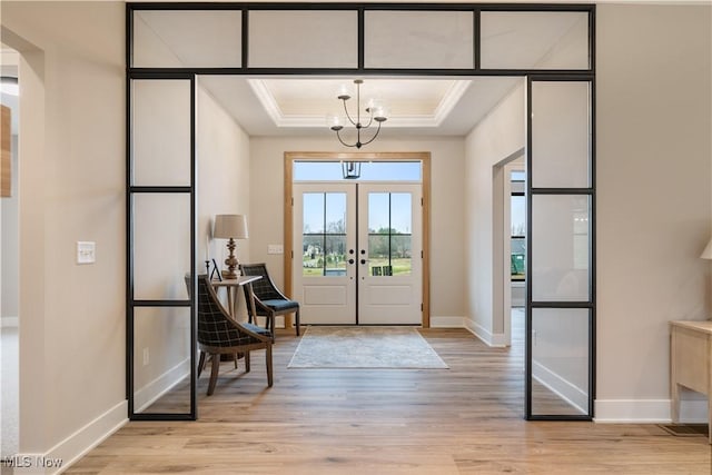 doorway to outside featuring a raised ceiling, french doors, a notable chandelier, and light wood-type flooring