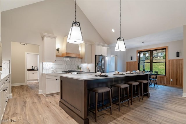 kitchen featuring white cabinets, pendant lighting, and a center island with sink