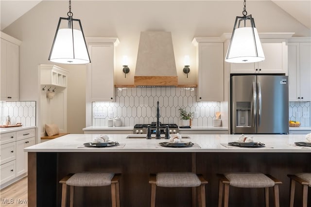 kitchen featuring pendant lighting, decorative backsplash, stainless steel fridge, and custom range hood