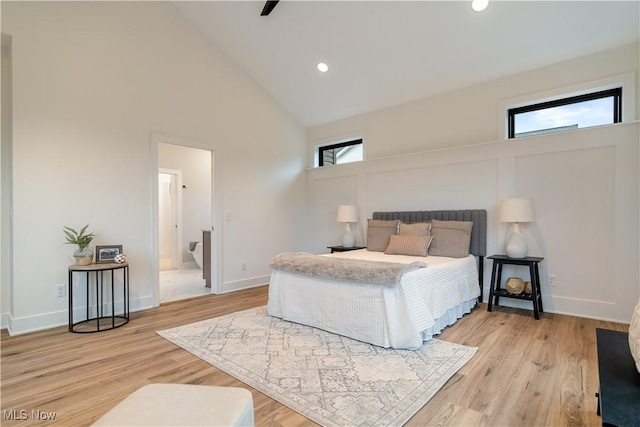 bedroom featuring connected bathroom, light hardwood / wood-style flooring, high vaulted ceiling, and ceiling fan