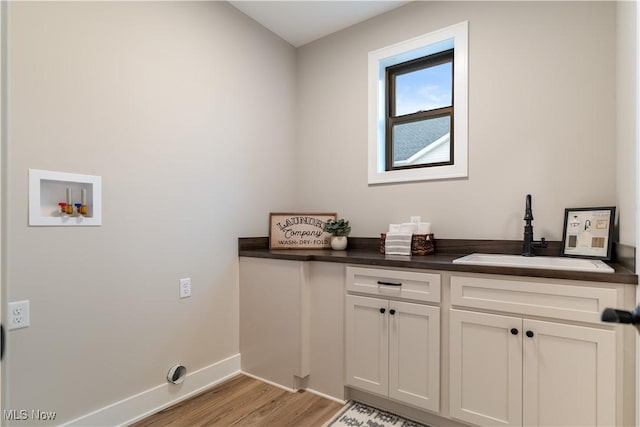 laundry area featuring washer hookup, light hardwood / wood-style floors, cabinets, and sink