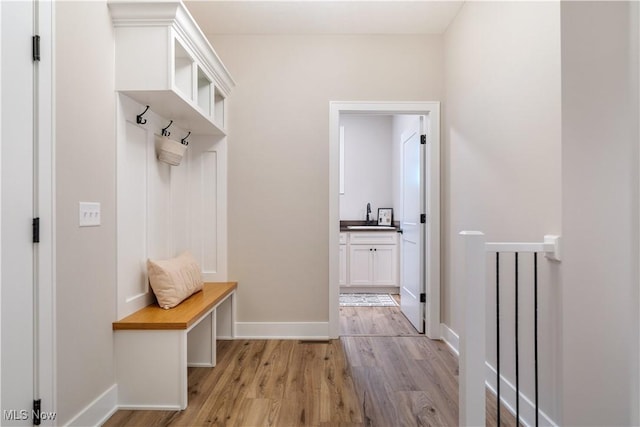 mudroom with sink and light hardwood / wood-style flooring