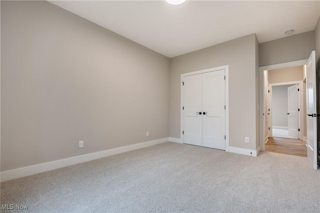 unfurnished bedroom featuring light colored carpet and a closet