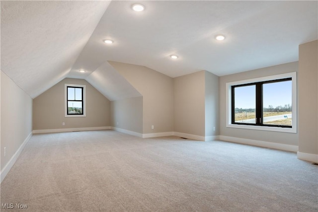 additional living space featuring light colored carpet and vaulted ceiling