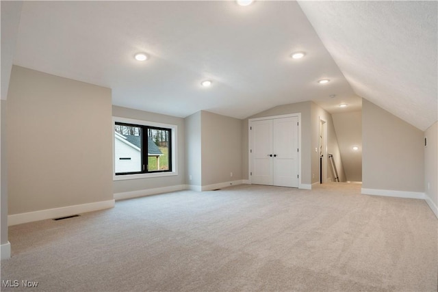 additional living space with light colored carpet and lofted ceiling