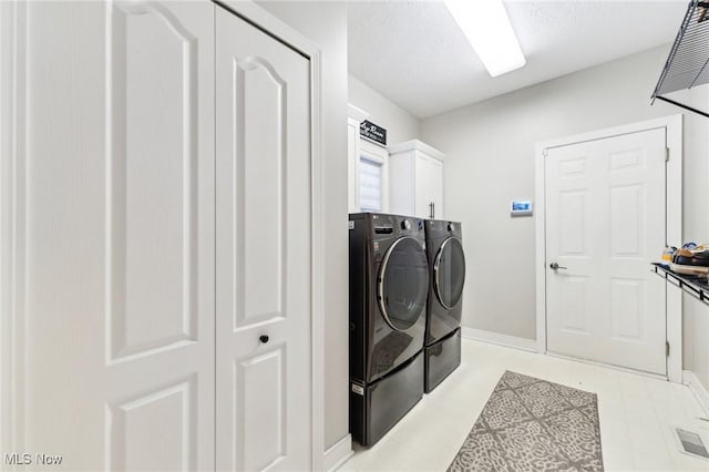 washroom featuring cabinets, washing machine and dryer, and a textured ceiling