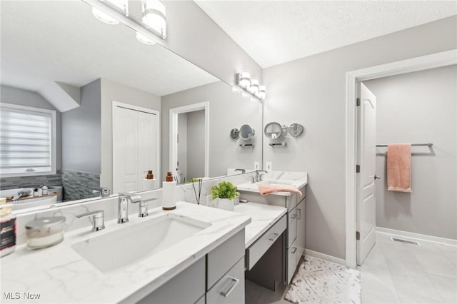 bathroom with tile patterned flooring, vanity, and a textured ceiling