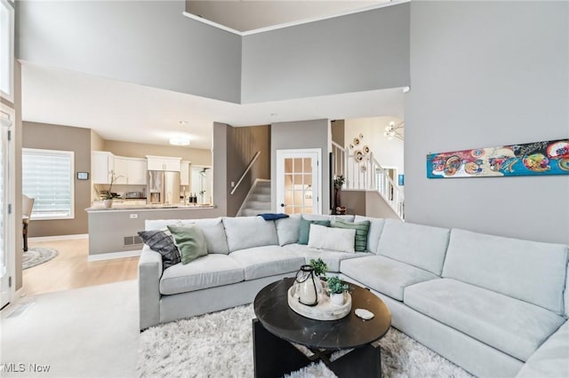 living room featuring light hardwood / wood-style flooring, a high ceiling, and ornamental molding