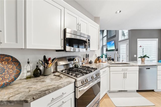 kitchen featuring white cabinets, light stone counters, sink, and appliances with stainless steel finishes