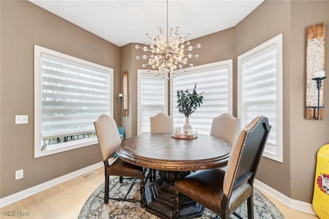 dining area with light hardwood / wood-style floors and an inviting chandelier