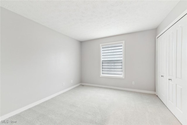 unfurnished bedroom featuring a closet, light colored carpet, and a textured ceiling