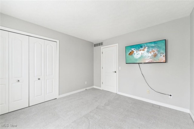 unfurnished bedroom with light carpet and a closet