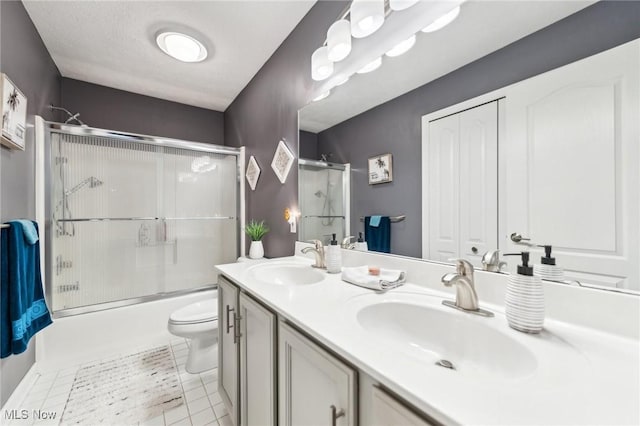 full bathroom featuring vanity, a textured ceiling, shower / bath combination with glass door, tile patterned flooring, and toilet