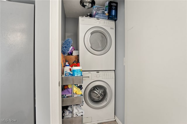 clothes washing area with a textured ceiling and stacked washer / drying machine