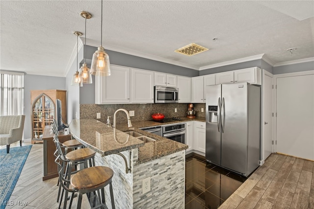 kitchen featuring kitchen peninsula, appliances with stainless steel finishes, white cabinetry, and pendant lighting