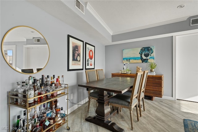 dining area featuring light wood-type flooring and crown molding