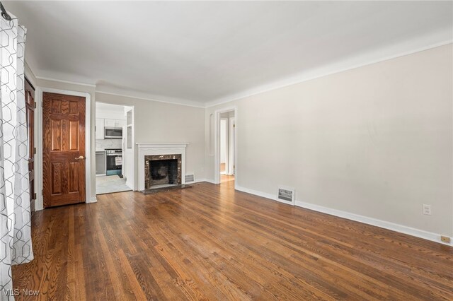 unfurnished living room featuring a premium fireplace and dark wood-type flooring