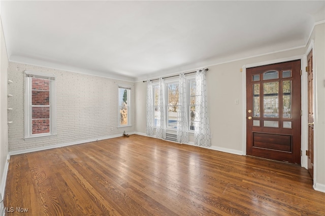 interior space with dark hardwood / wood-style floors and brick wall