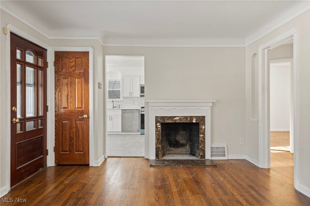 unfurnished living room with a fireplace, crown molding, and dark wood-type flooring