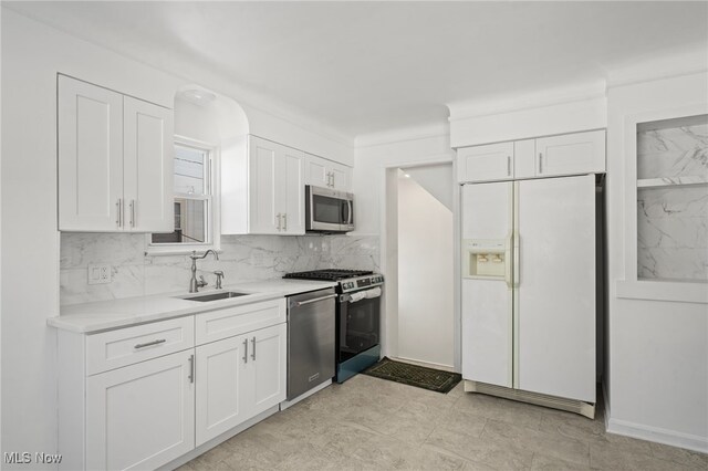 kitchen with white cabinets, decorative backsplash, stainless steel appliances, and sink