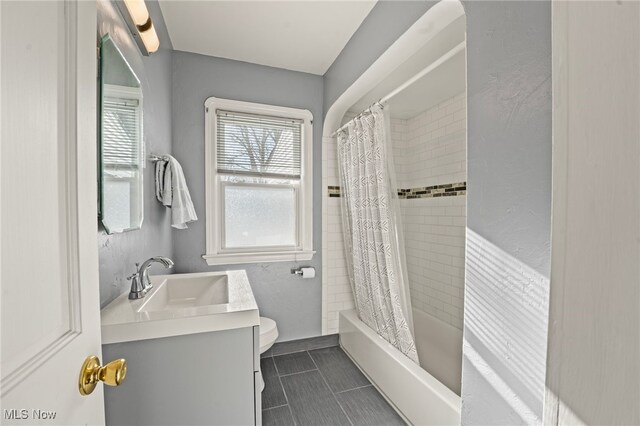 full bathroom featuring tile patterned floors, shower / tub combo with curtain, vanity, and toilet