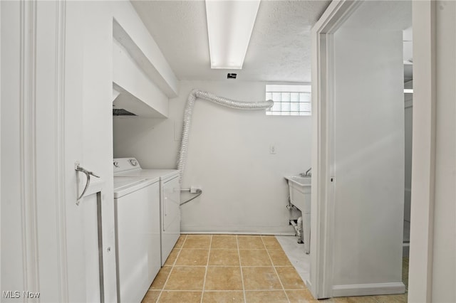 washroom featuring a textured ceiling, washer and clothes dryer, and light tile patterned flooring