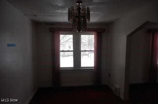 unfurnished dining area featuring a chandelier