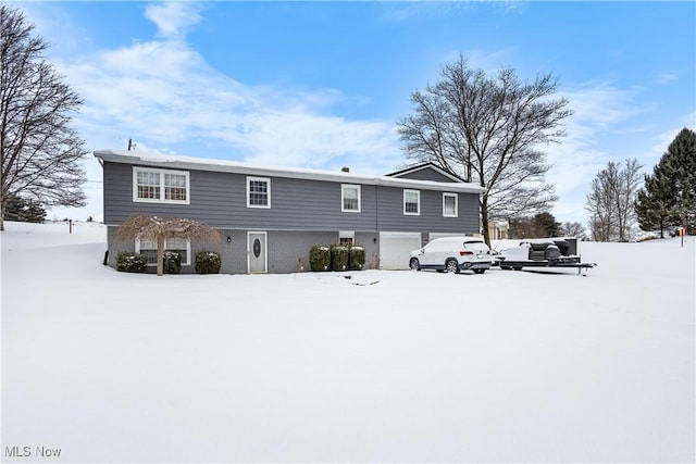 snow covered rear of property with a garage