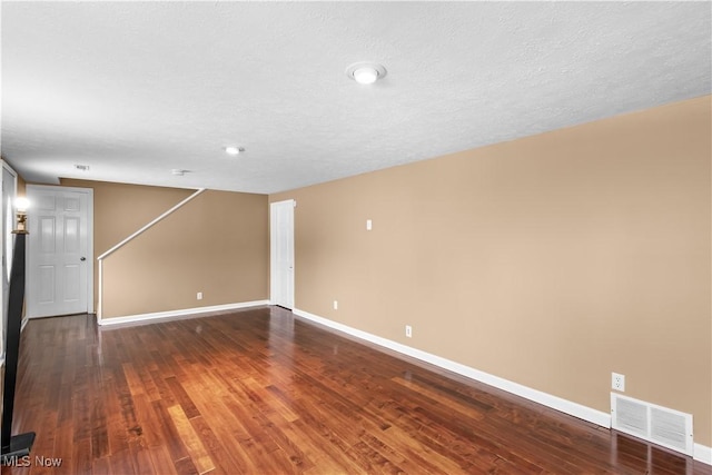 spare room with dark hardwood / wood-style floors and a textured ceiling