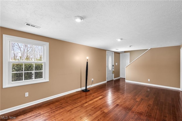 empty room featuring wood-type flooring and a textured ceiling