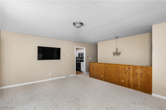 carpeted spare room featuring a textured ceiling and a notable chandelier