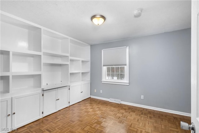 spare room with a textured ceiling and light parquet floors