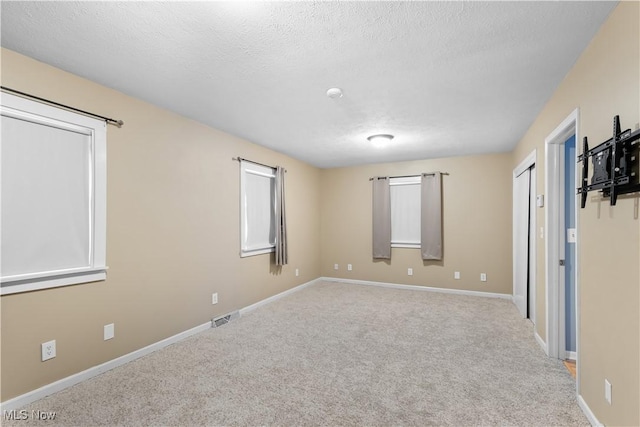 unfurnished room featuring a textured ceiling and light colored carpet