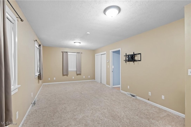 carpeted empty room with a textured ceiling