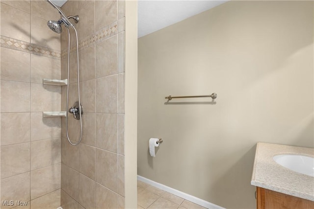 bathroom with tile patterned flooring, vanity, and tiled shower