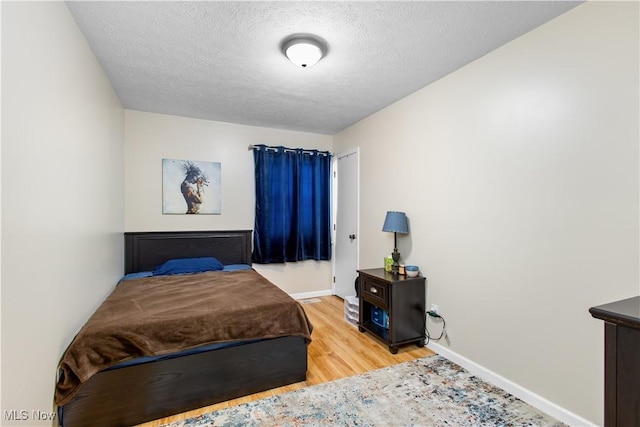 bedroom with light hardwood / wood-style floors and a textured ceiling