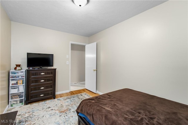 bedroom with light wood-type flooring and a textured ceiling