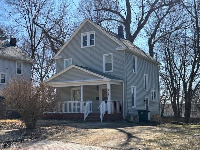 american foursquare style home with a porch and a chimney