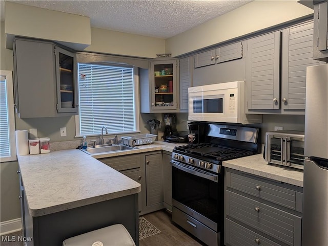 kitchen featuring appliances with stainless steel finishes, kitchen peninsula, sink, and gray cabinetry