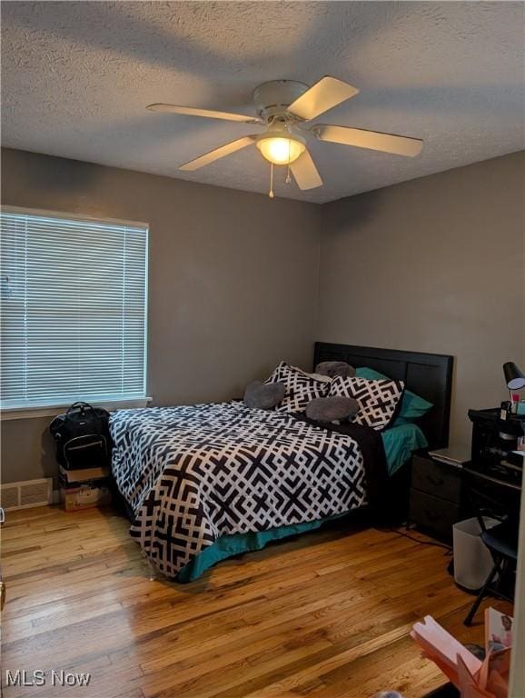 bedroom featuring a textured ceiling, light hardwood / wood-style flooring, and ceiling fan